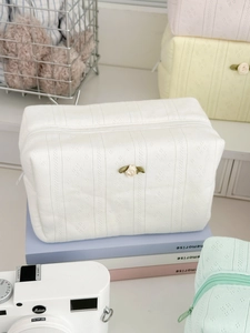 Close-up of quilted knit cosmetic bags in pastel colors with floral rose accents