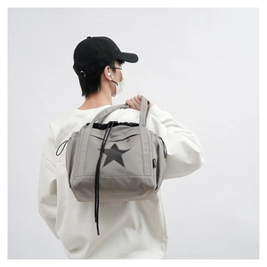 Detail of grey crossbody bag with black star print worn by male model on white background