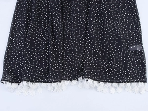 Detailed view of the black polka dot chiffon dress hem with delicate white lace fringe