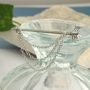Detail of silver arrow industrial earring with triple chain dangles on a natural background