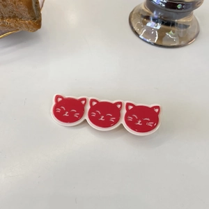 Close-up of triple cat head hair clips in red and cream resin finish for hair styling