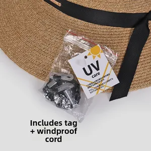 Detail of woven straw sun hat with black ribbon, UV protection tag and windproof strap