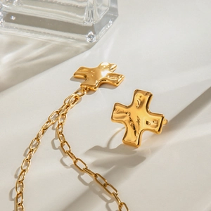 Golden stainless steel hammered cross earrings set with delicate chain detail on white base