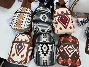 Detail view of ethnic canvas sling bags with geometric patterns and zipper closures