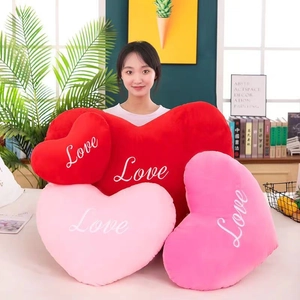 Detail showing plush red and pink heart-shaped pillows with Love embroidery in a cozy room