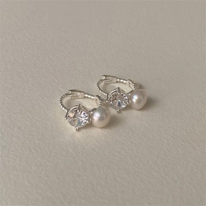 Detail shot of silver twisted hoop earrings with round zircon and small white pearl