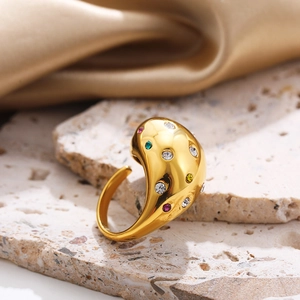 Detailed view of gold plated titanium steel ring with colorful zircons on stone surface