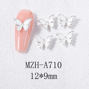 Vue macro de breloques à ongles papillon 3D avec cadre argenté et émail blanc