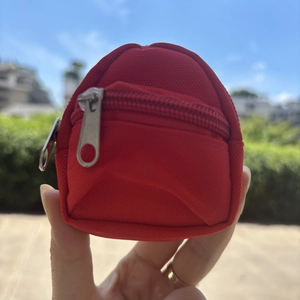 Close-up of red mini backpack keychain coin purse with double metal zippers held in hand