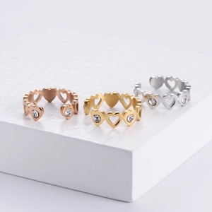 Detailed view of hollow heart rings with inlaid crystals in gold, rose gold and silver