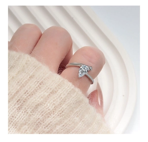 Macro shot of silver ring with pear-cut stone and micro-pave diamonds on model