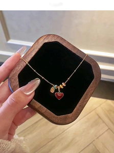 Detail of 18k gold plated necklace featuring a red enamel heart pendant and colorful beads