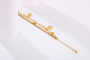 Detail showing a double-layer gold titanium steel bracelet with Hamsa hand and bead charms