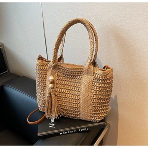Close-up of a straw tote bag with wood bead tassels and a detachable shoulder strap