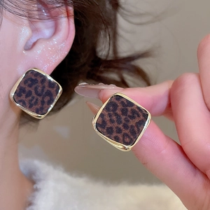 Gros plan de boucles d'oreilles carrées imprimé léopard avec bords dorés sur modèle