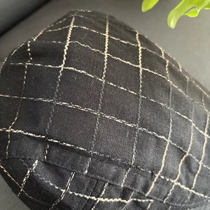 Macro shot of breathable linen blend fabric with quilted plaid stitching on a flat cap