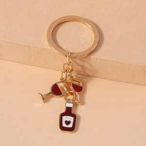 Detail of red wine bottle and glass keychain with gold metal clasp and red enamel finish