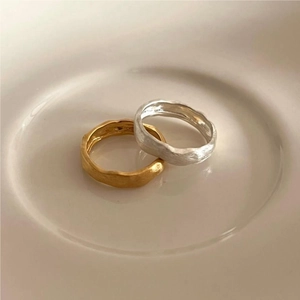 Detail of irregular hammer textured gold and silver rings on a light ceramic plate