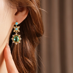 Détail macro de boucles d'oreilles vintage en or avec pierre ovale verte et turquoise