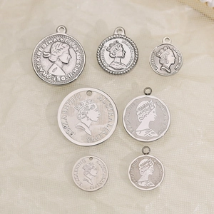 Stainless steel Queen Elizabeth II coin pendants in various sizes on beige fabric