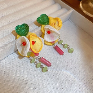 Detailed macro view of handmade fabric flower earrings with green heart and colorful beads