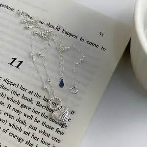 Vintage silver heart necklace with radial carvings and beaded chain on an antique book
