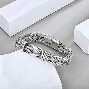 Detail of silver double-row woven chain bracelet with knot design and magnetic clasp