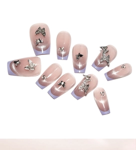 Detail view of purple cat-eye press-on nails with 3D silver metal butterflies and rhinestones