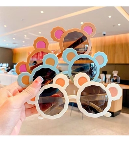Detailed view of multiple colorful cartoon bear ear sunglasses for children held in hand