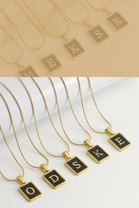 Detail of 18k gold plated snake chain with a rectangular black enamel letter pendant