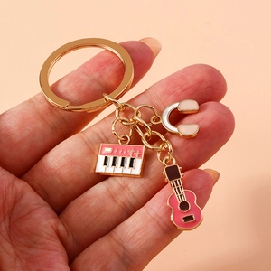 Golden musical keychain with pink enamel guitar, keyboard and headphones pendants