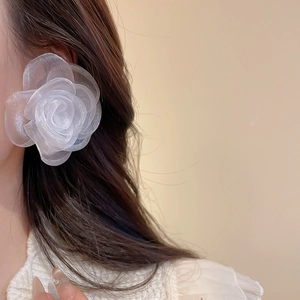 Close-up of elegant white 3D fabric flower earring with a layered organza petal design