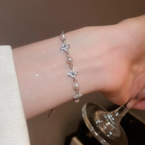 Close-up of pearl bracelet with silver flower charms and zircon inlay on model wrist