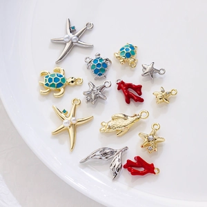 Golden and silver ocean-themed pendants including starfish and sea turtles on a ceramic plate
