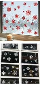 Detail showing glittery red and white snowflake window clings with warm candle light