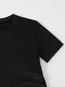 Detail of black tankini swim top featuring ruched side drawstrings and raglan sleeves