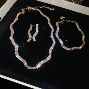 Detailed close-up of gold wavy jewelry set with necklaces and earrings on black velvet