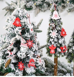 Close-up of red and white wooden Christmas ornaments hanging on a snowy festive tree