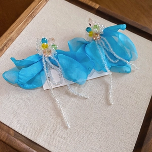 Macro shot of blue fabric flower earrings with crystal beads and glass tassel fringe