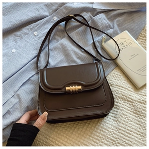 Détail d'un sac besace en cuir marron foncé avec un fermoir cylindrique doré élégant