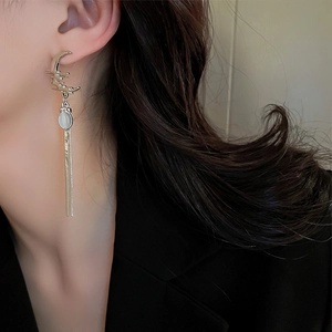 Close-up of elegant silver moon earrings with tassels and cat-eye stone on a model