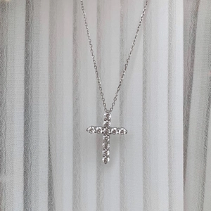 Macro shot of silver cross pendant with shimmering cubic zirconia and delicate cable chain