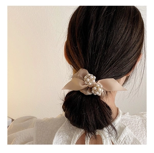 Gros plan d'un chouchou nœud en satin champagne avec perles sur un chignon