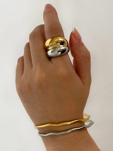 Detail of chunky two-tone gold and silver ring with polished wavy texture bangles