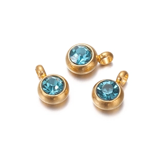 Detail of three gold earrings with sparkling blue zircon stones and round drop pendants