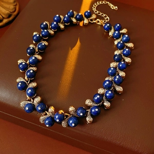 Detail of vintage necklace with deep blue beads and textured gold metal chain links