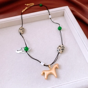 Détail du collier de perles avec pendentif cheval doré et pierres sur soie