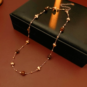 Dettaglio della collana con perle occhio di tigre e catena placcata oro in scatola