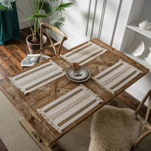 Set of 4 bohemian woven placemats with brown stripes and tassels on a wooden table