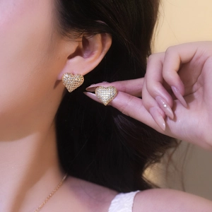 Elegant gold heart stud earrings with sparkling pave zircon on a model's ear